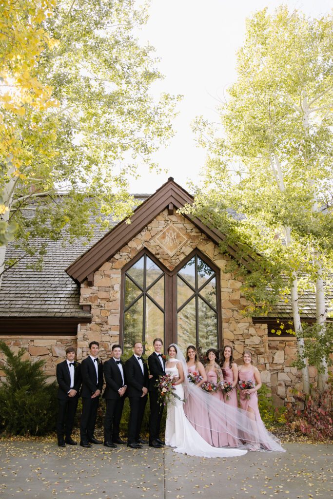 bride and groom standing with their best friends in front of the church after the ceremony featuring stunning fall colors.