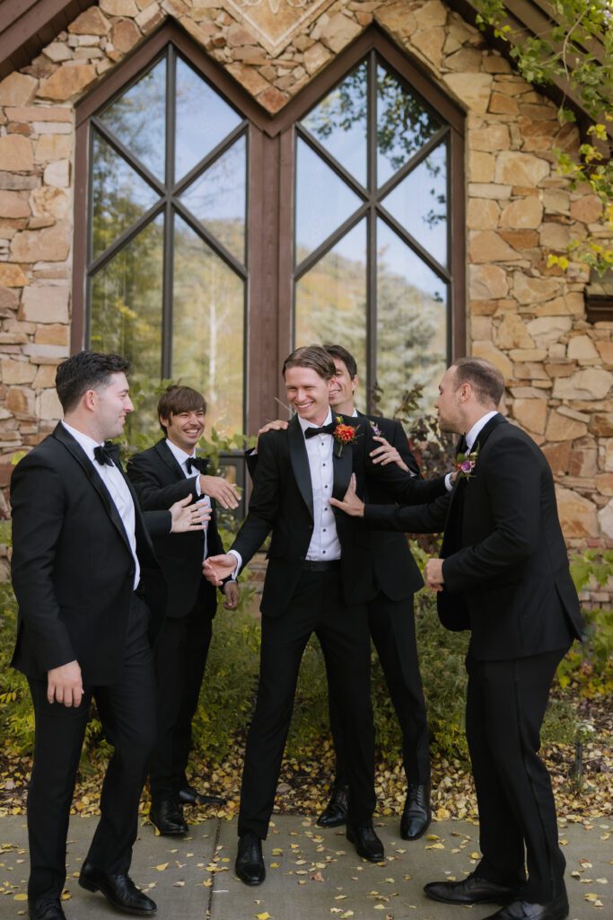 a candid moment with the groom with his best friends in front of the church after the ceremony featuring stunning fall colors.
