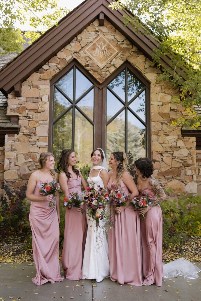 bride standing with her best friends in front of the church after the ceremony featuring stunning fall colors.