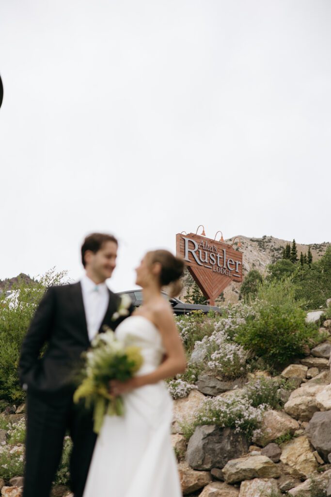 bride and groom in front of the venue sign