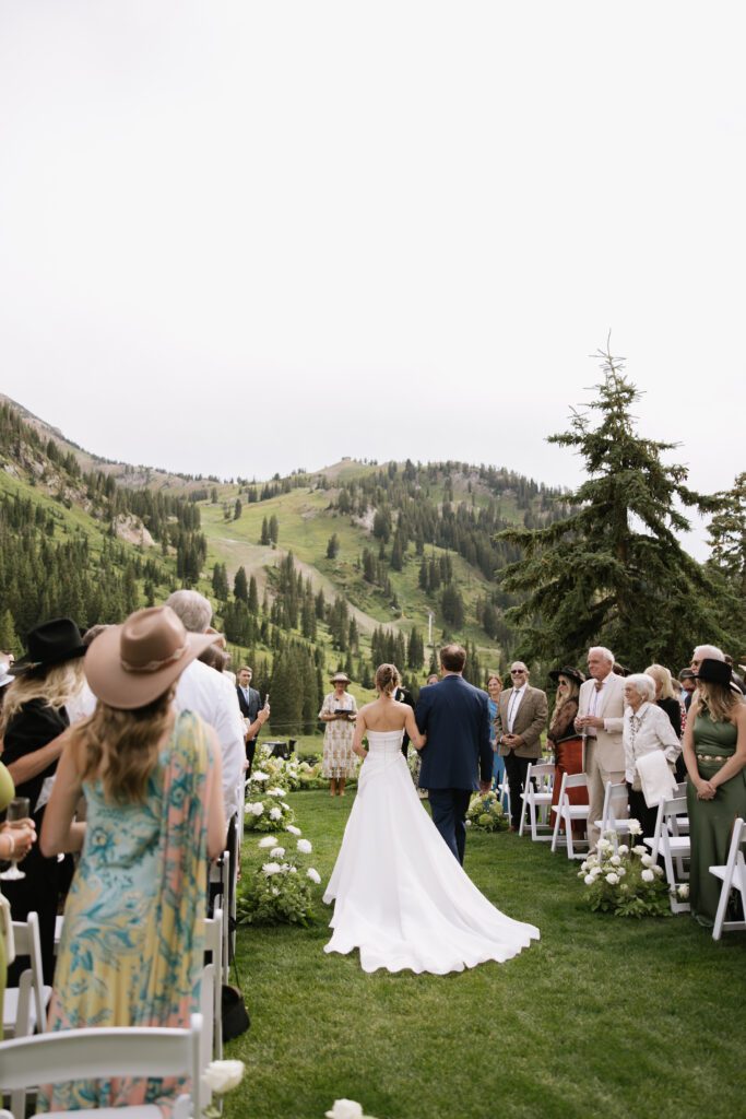 S and P during their Alta’s Rustler Lodge wedding ceremony with green mountains behind them.