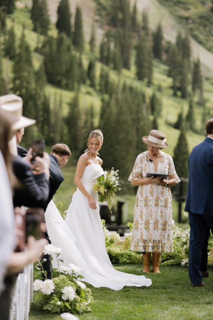 S and P during their Alta’s Rustler Lodge wedding ceremony with green mountains behind them.