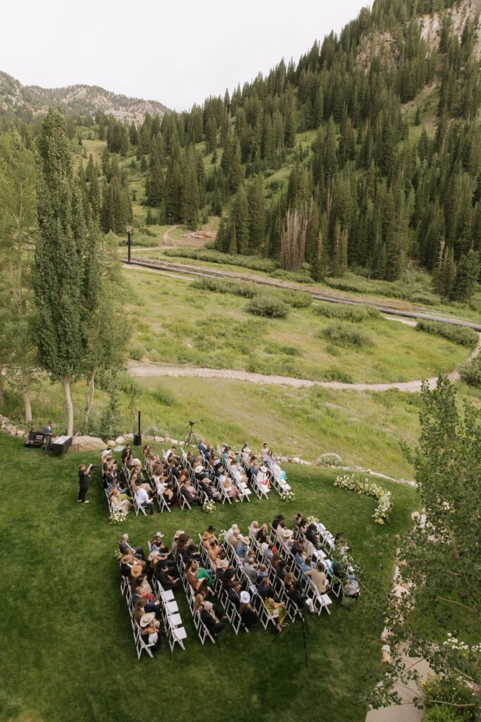 S and P during their Alta’s Rustler Lodge wedding ceremony with green mountains behind them.