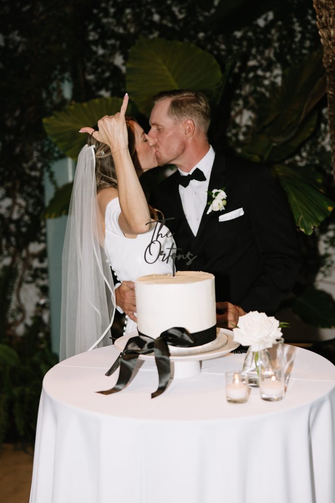 A + M kissing after cutting their wedding cake during the reception at Red Butte Gardens.