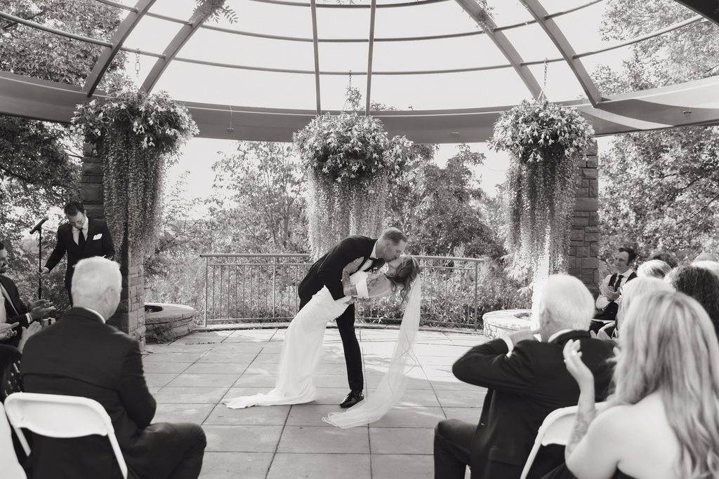 A and M kissing kissing after ceremony at Red Butte Garden, surrounded by greenery.