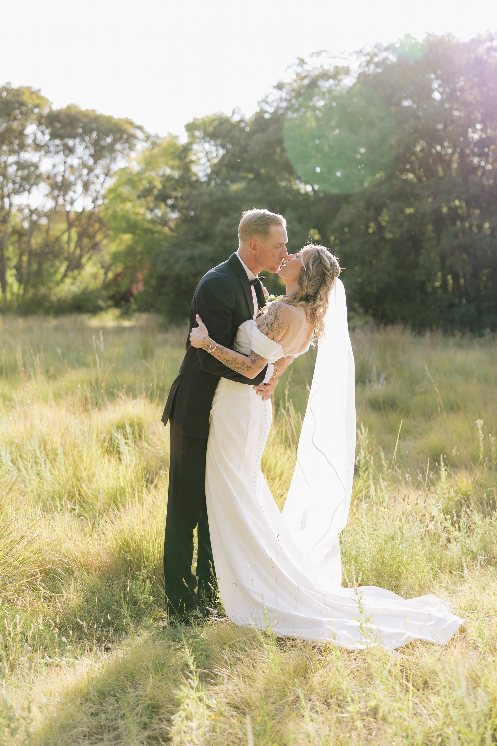 A and M kissing in field at Red Butte Garden, surrounded by greenery.